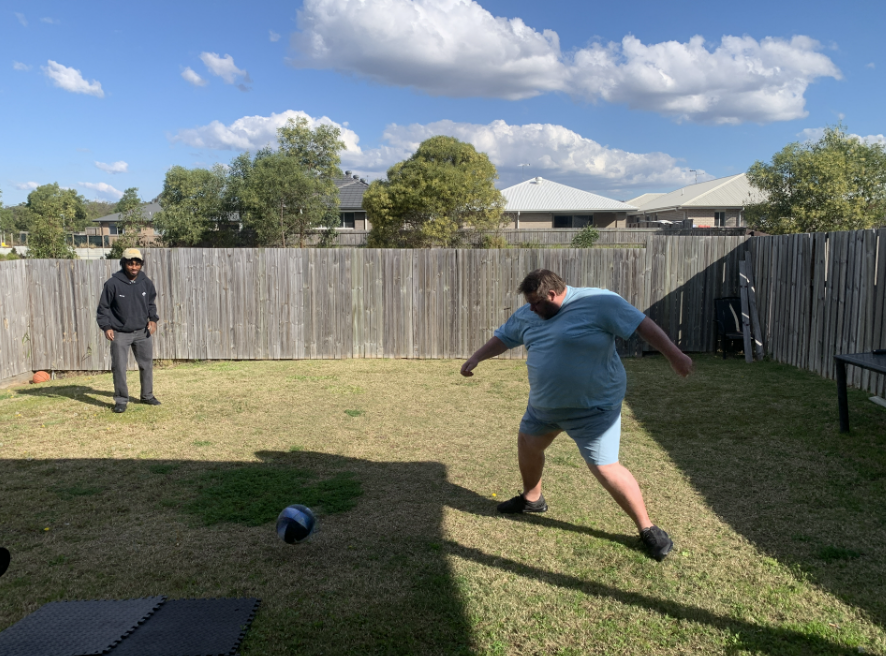 Xavier kicking a football in a backyard